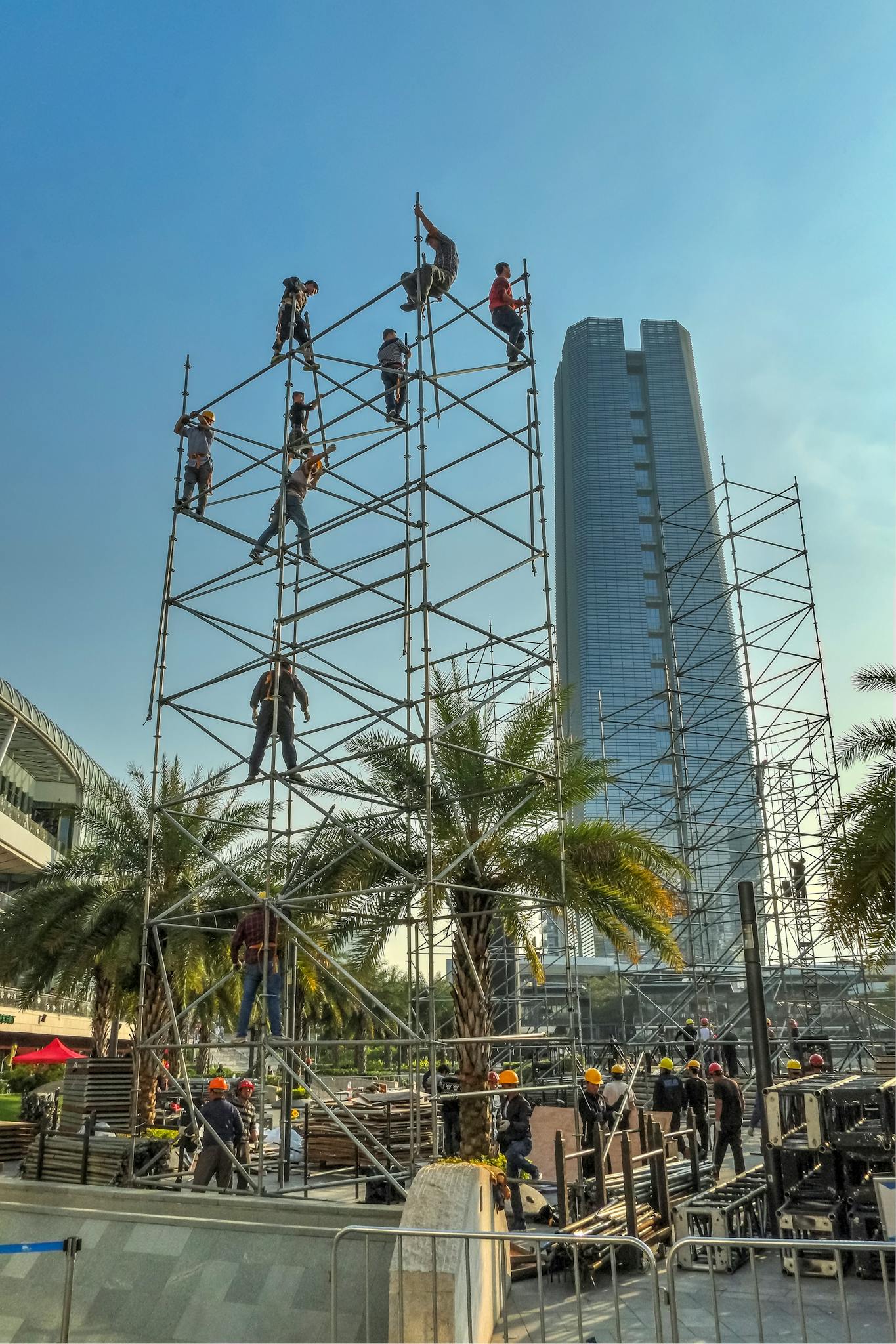 Skilled workers building scaffolding at a construction site in Shenzhen with a skyscraper in the background.